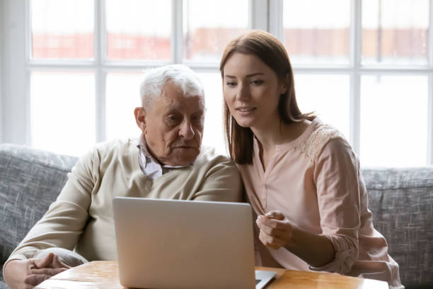 istock Female volunteer assisting elderly man in shopping online using computer 1311337348