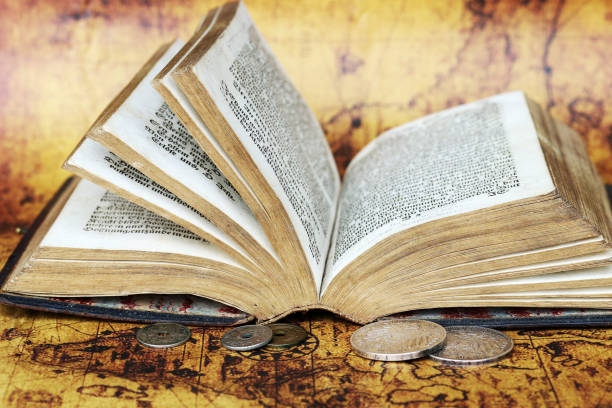 istock Old silver coins from 1902 and an antique book from 1763 on a world map 1311337391