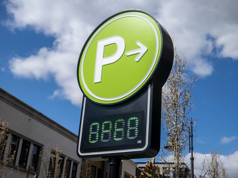 Low angle view of a lime green digital parking sign for a parking garage in a shopping district downtown