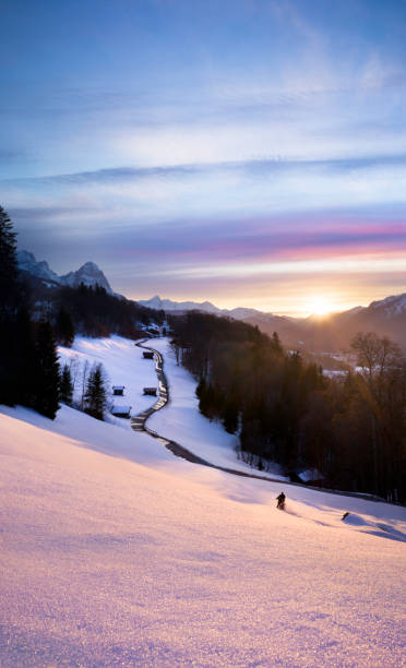 bellissimo tramonto rosa in montagna con strada di linea principale verso chiesa e motociclista che si divertono nella neve fresca - waxenstein foto e immagini stock