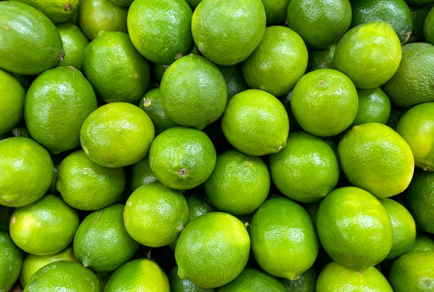 ярко-зеленая куча кучу запасов лайма лаймы на фермерском рынке продуктовый фруктовый стенд - lime стоковые фото и изображения