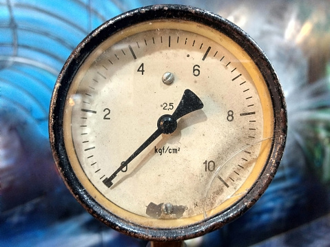 Old vintage rusty psi bar pressure measurement gauge installed on hydraulic equipment