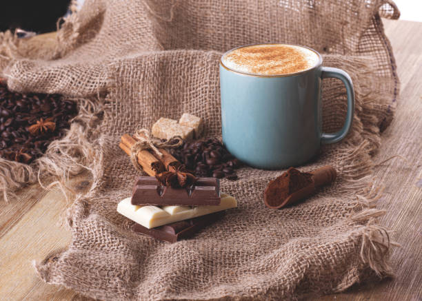 ahşap arka plan üzerinde bir fincan kahve, çikolata, fasulye, anason ve tarçın stok fotoğrafı