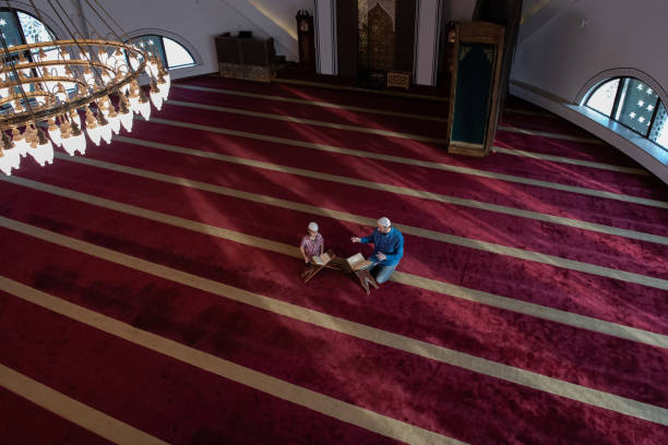 father and son reading holly book quran together islamic education concept muslim prayer father and son in mosque praying and reading holly book quran together father allah stock pictures, royalty-free photos & images