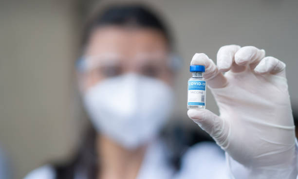 Healthcare worker holding a COVID-19 vaccine ampoule Latin American healthcare worker holding a COVID-19 vaccine ampoule at a vaccination stand â coronavirus pandemic concepts ampoule photos stock pictures, royalty-free photos & images