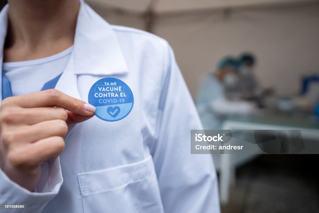 Close-up on a doctor wearing a COVID-19 vaccination sticker in Spanish Close-up on a doctor wearing a COVID-19 vaccination sticker in Spanish after getting her vaccine - immunization program concepts. **DESIGN ON STICKER WAS MADE FROM SCRATCH BY US** Sticker Stock Photo