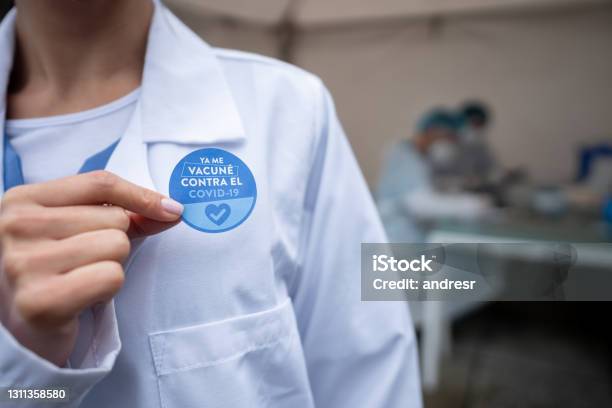 Closeup On A Doctor Wearing A Covid19 Vaccination Sticker In Spanish Stock Photo - Download Image Now