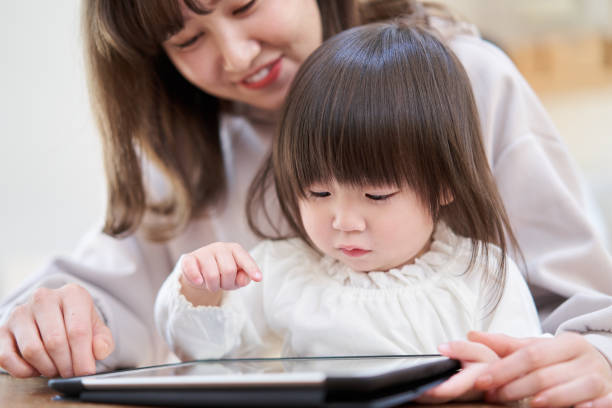 お母さんとタブレットを見てアジアの女の子 - 子供　習い事 ストックフォトと画像