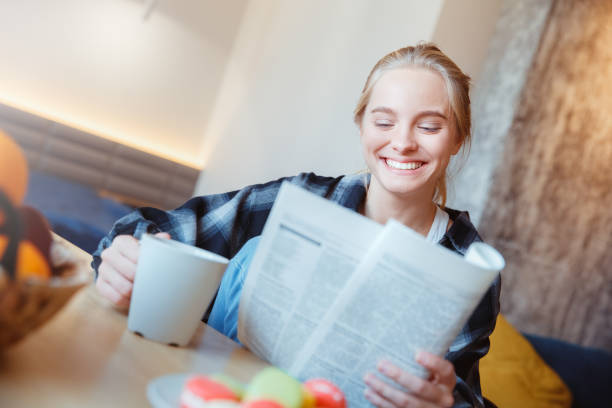istock Young woman at home in the kitchen drinking tea reading newspaper 1311367069