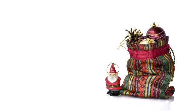 Santa Claus figurine stands guard over a bag full of Christmas balls and fir cones.