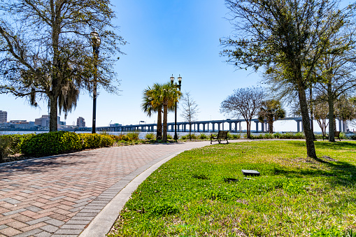 A park bench along the sidewalk of a landscaped public park along the Jacksonville Riverwalk.