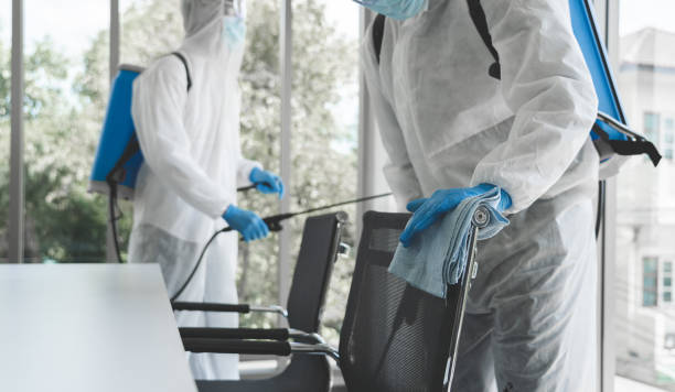 Man in virus protective suit and mask spraying alcohol cleaning covid19 infected area, Virus disinfection concept stock photo