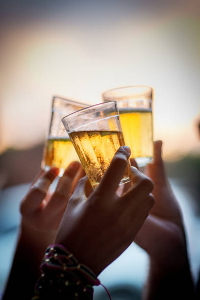 Hands toasting with glasses of beer in the late afternoon. stock photo