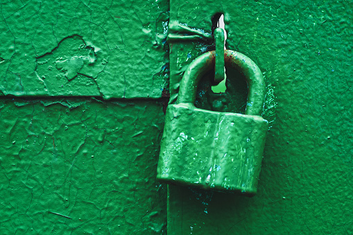 Old padlock on closed gate painted with green enamel, copy space