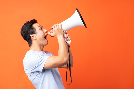 Asian man holding megaphone and shouting
