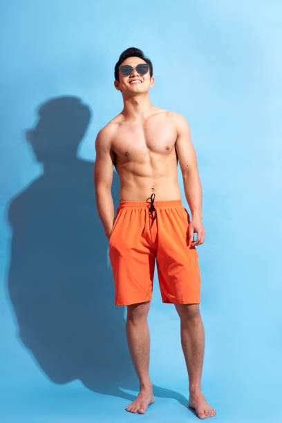Man on background Handsome asian man with bare body on blue background bathing suit stock pictures, royalty-free photos & images