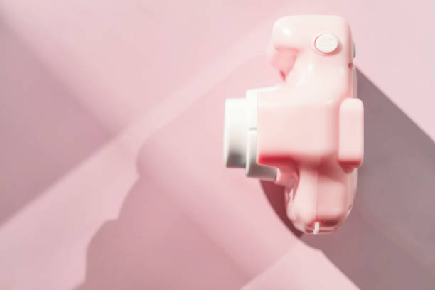 Light pink toy camera on pastel background, top view, shadow. Future digital photographer device