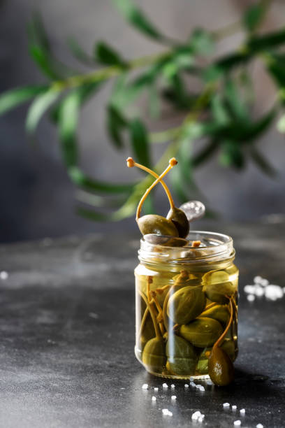 istock Marinated or pickled canned capers fruit close up in jar on gray kitchen table with copy space 1311380659