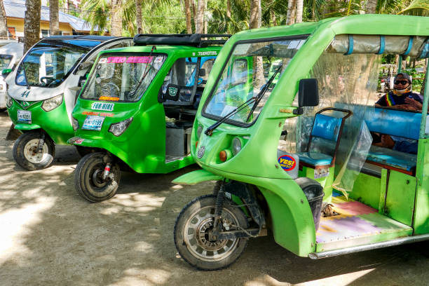 Environmentally friendly electric trikes, Boracay Three green colored electric trikes parking near Cagban Port on Boracay Island, Philippines, waiting for passengers. One driver visible inside trike. philippines tricycle stock pictures, royalty-free photos & images