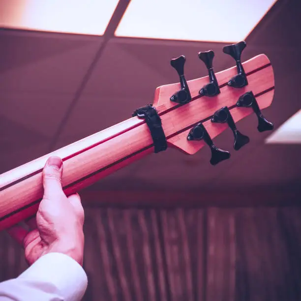 Photo of The guitarist's hand on the neck of a six-string bass guitar