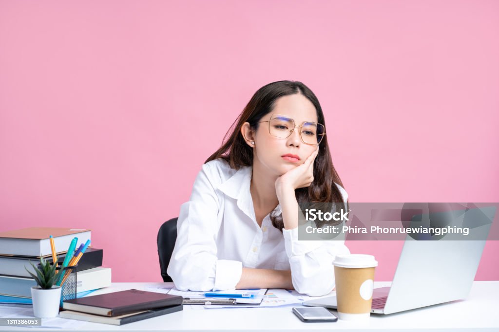 Young Asian women are tired from office work. Isolated Pastel Pink Background. Working Stock Photo