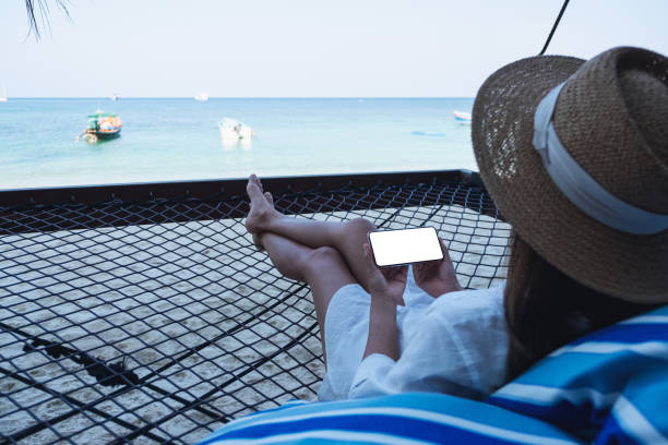 istock a woman holding mobile phone with blank desktop screen while lying down on hammock on the beach 1311391841