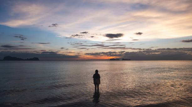 istock a woman walking in the sea before sunset 1311391846