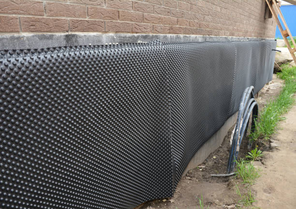 proteger la base del sótano fuera de una casa de ladrillos del agua y la humedad utilizando una membrana dimpled de impermeabilización de la base, barrera para las paredes exteriores. impermeabilización de la fundación casa. - impermeable fotografías e imágenes de stock