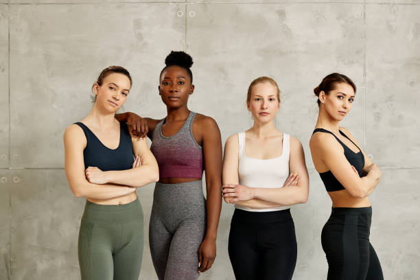 Portrait of confident diverse female athletes against the wall looking at camera. Portrait of confident multi-ethnic group of sportswomen against the wall. Copy space. sports bra stock pictures, royalty-free photos & images