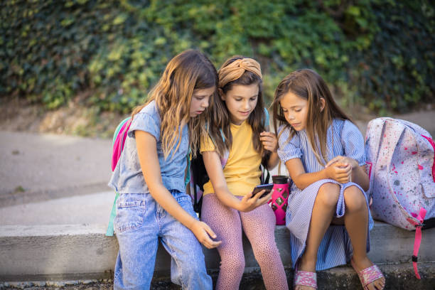 istock Three school girls using smart phone together. 1311393912