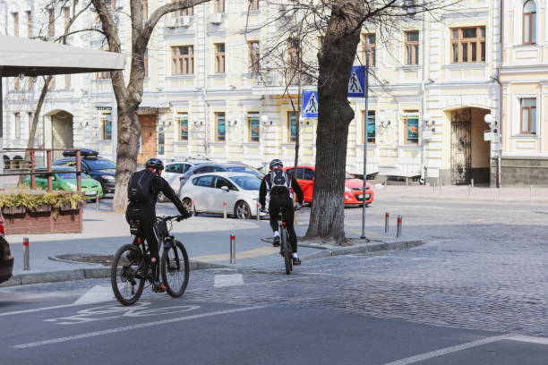 en la ciudad del encierro. ciclistas y pocos peatones caminan por calles vacías. - unmasked fotografías e imágenes de stock