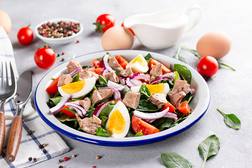 Salad from cod liver, eggs and vegetables on a white plate. Nutritious, useful.