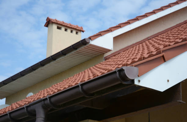 istock A close-up of a rain gutter with a stop end and running outlet installed correctly a few inches lower than the roofline with a blurred soffit, rooftop and chimney in the background. 1311396257