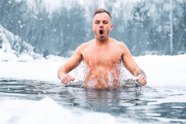 Photo of Man jumping in cold water in winter