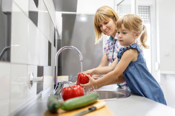 istock Mother and daughter washing vegetables 1311402565