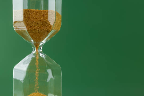 istock Gold hourglass on dark green paper background 1311403945