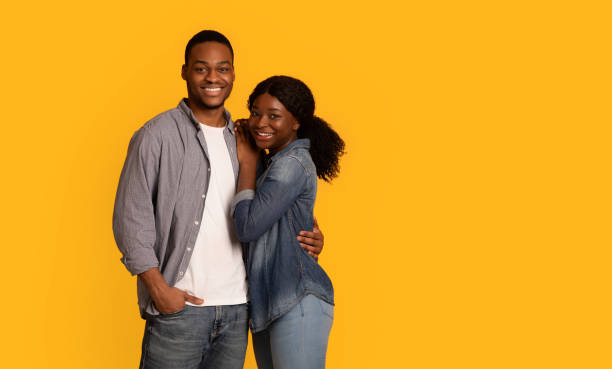 istock Cheerful young black couple embracing each other while posing over yellow background 1311404959