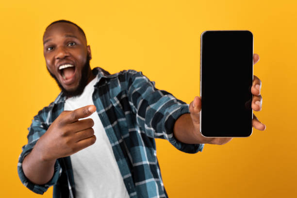 istock Excited Black Guy Showing Mobile Phone Screen On Yellow Background 1311405073