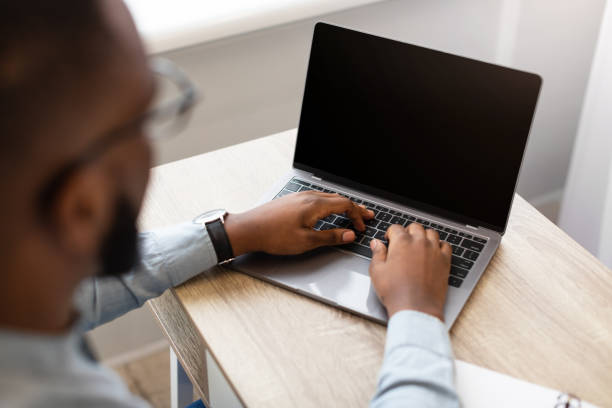 istock Black Businessman Using Laptop With Empty Screen Indoor, High-Angle View 1311405145