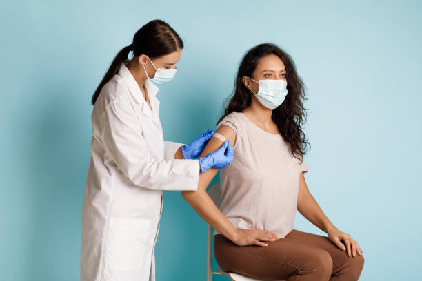 istock Female Getting Vaccinated, Nurse Applying Plaster On Arm, Blue Background 1311406457