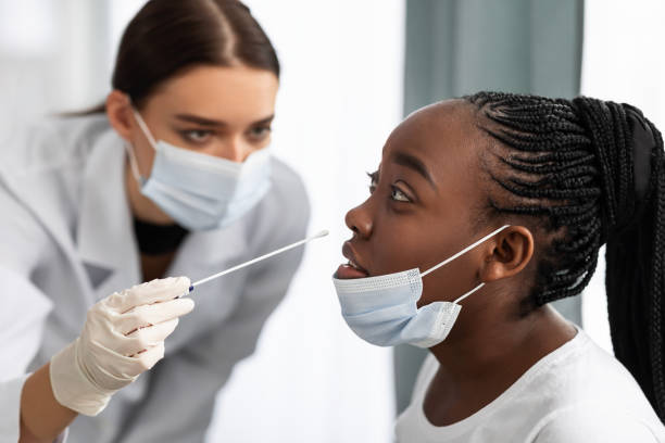 istock Doctor taking PCR test sample from potentially infected black female 1311406575