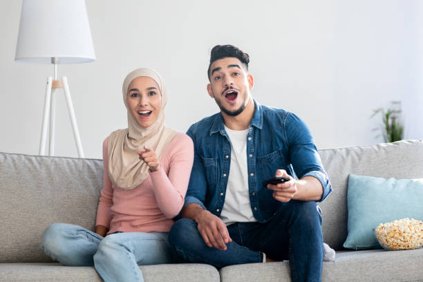 istock Excited middle-eastern couple switching TV channels at home 1311406854