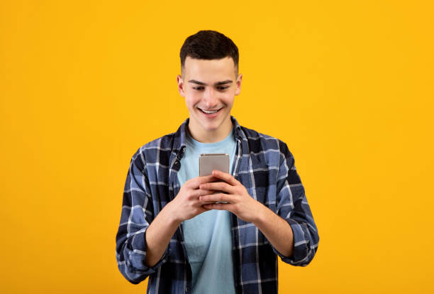 istock Joyful young guy in casual wear using tablet pc for online work or education on orange studio background 1311408124