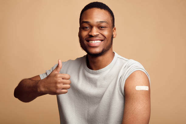 istock Vaccinated Guy With Plaster On Arm Gesturing Thumbs-Up, Beige Background 1311408684