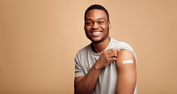 Retrato del hombre africano vacunado mostrando su brazo, fondo beige photo