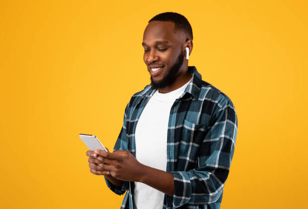 istock African Man Using Phone Wearing Earbuds Standing Over Yellow Background 1311410343