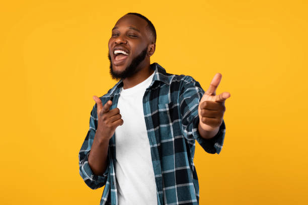 istock Cheerful African Guy Pointing Fingers At Camera Over Yellow Background 1311410424