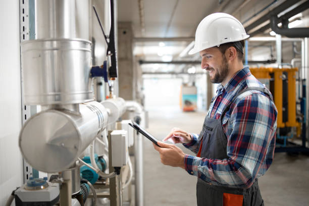 ingegnere del riscaldamento che tiene il tablet computer e fissa i parametri dell'impianto di riscaldamento nel locale caldaia di fabbrica. - oil pressure foto e immagini stock