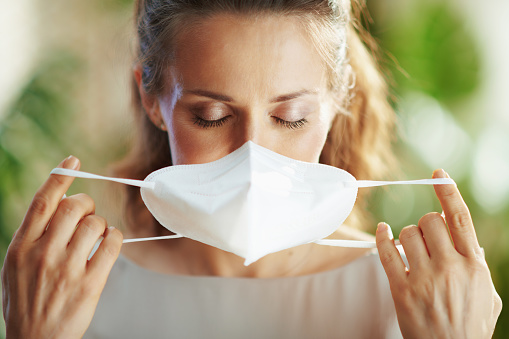 coronavirus pandemic. young female in grey blouse wearing ffp2 mask.