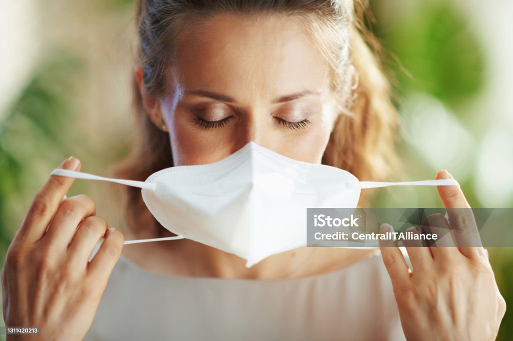 young female in grey blouse wearing ffp2 mask coronavirus pandemic. young female in grey blouse wearing ffp2 mask. Facial Mask - Beauty Product Stock Photo